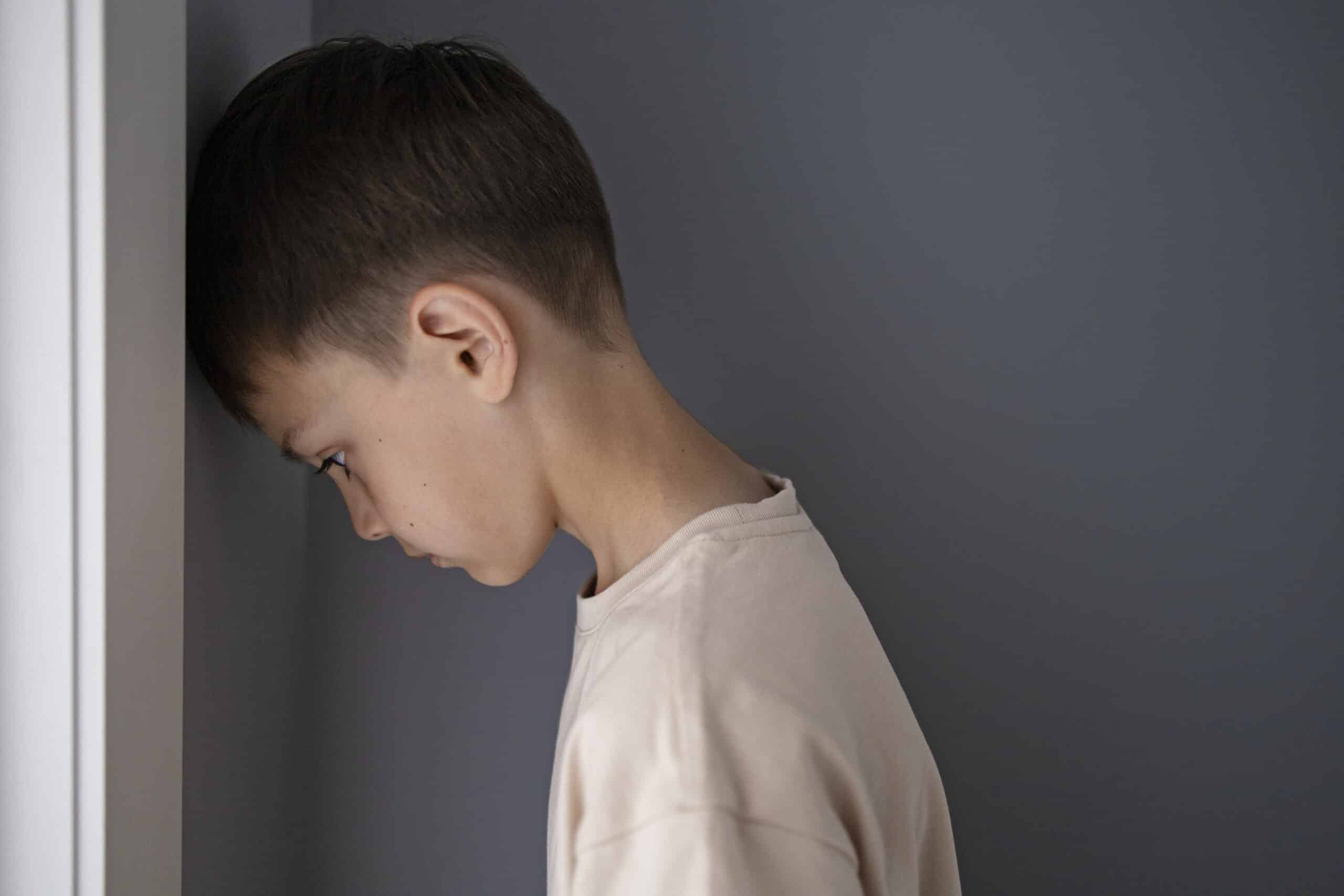 Boy resting his head on a wall.