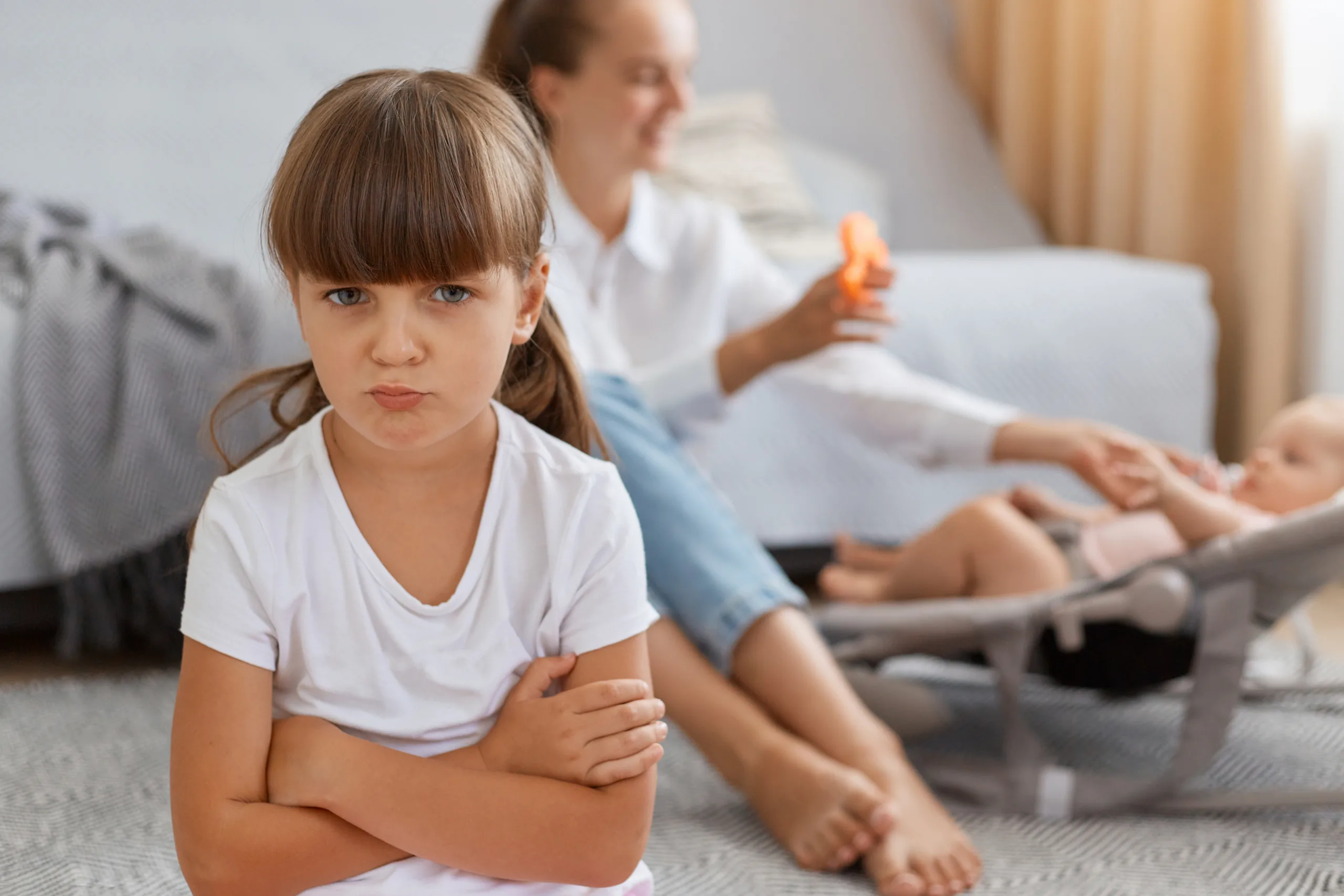 Portrait of dark haired little girl wearing white t-shirt posing with pout lips and unhappy