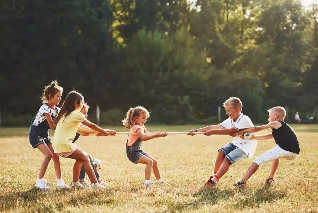 kids playing tug of war game in the beautiful meadow at sunny day