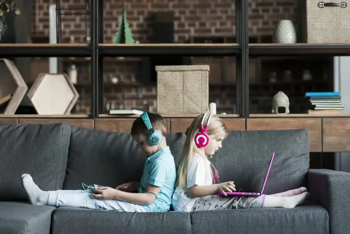 Brother and sister immersed in screen time, comfortably seated on the couch