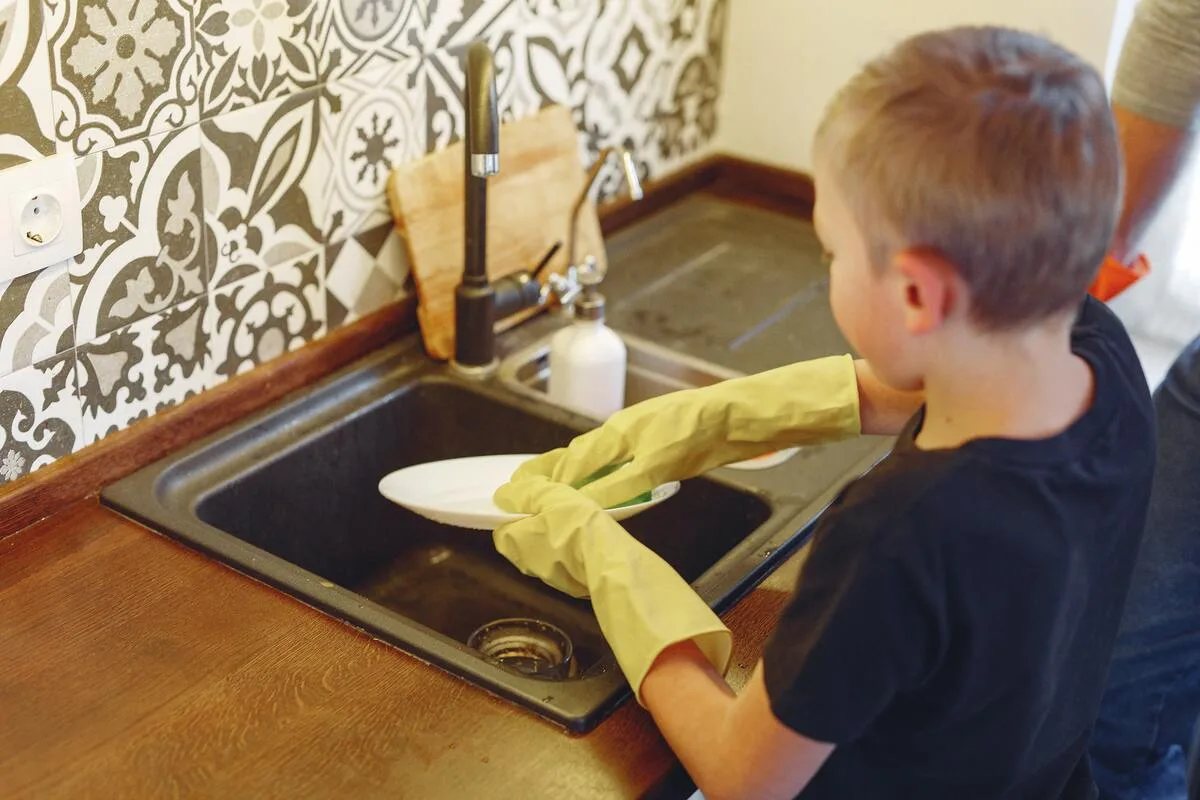 Young boy in the kitchen washing a plate