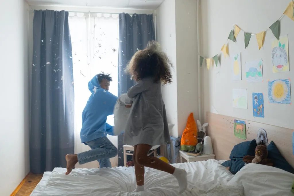 Two brothers having a playful pillow fight in bed.