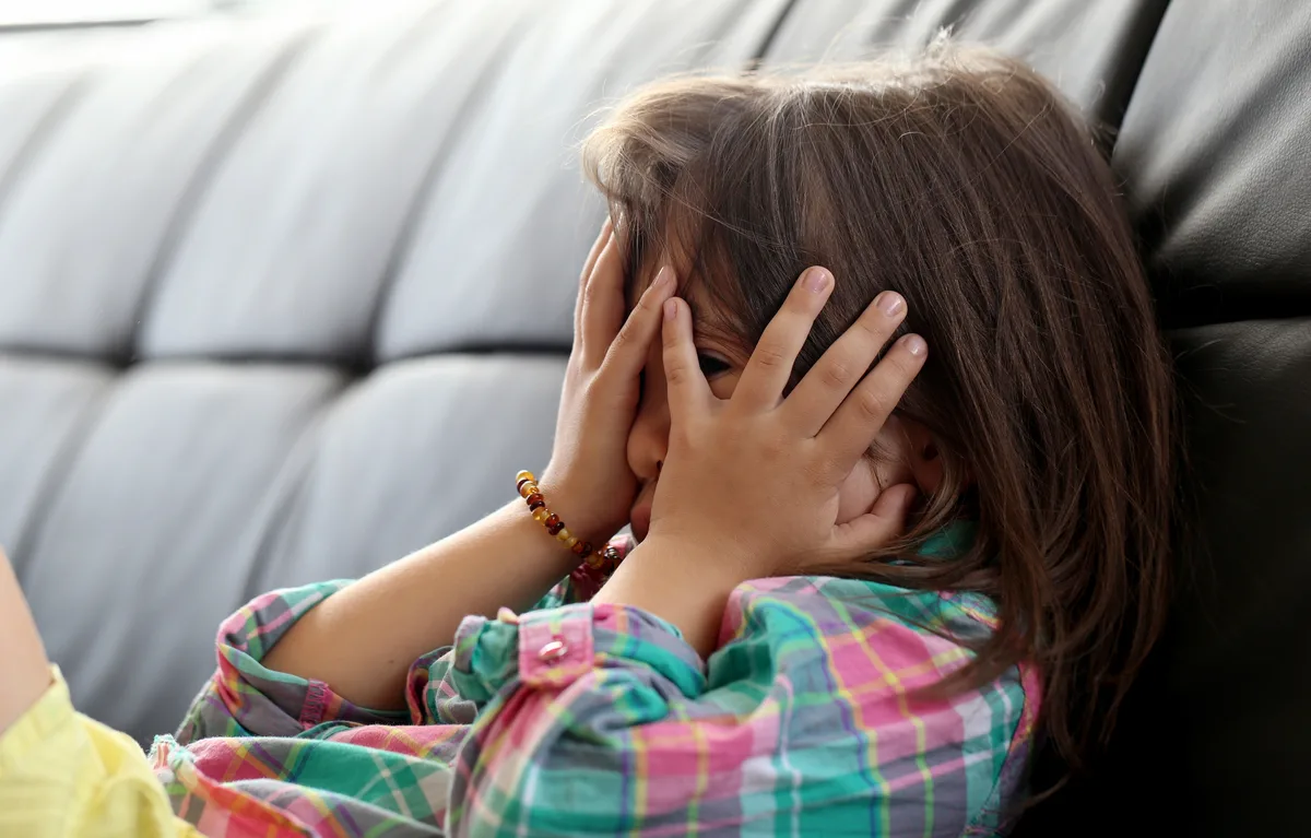 Child covering his face with hands and peaking through fingers