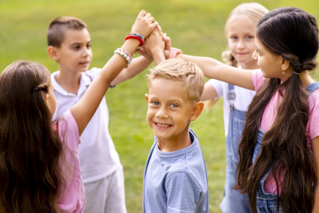 Team of five boys and girls putting their hands together