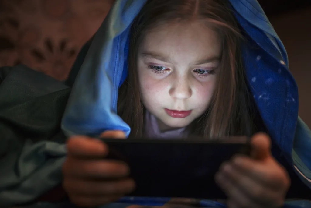 Girls looking at a screen under covers