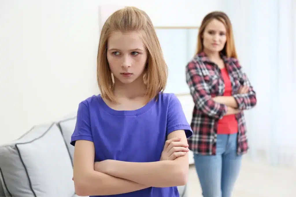 A girl in the center and mother in the background having a disagreement