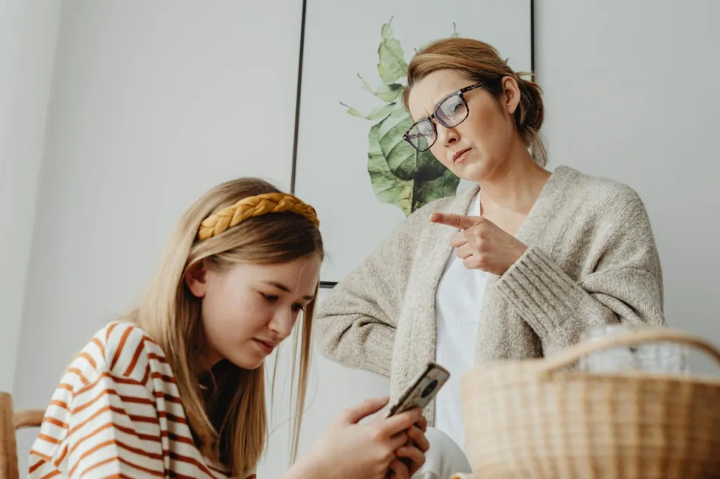 Concerned mom gesturing and advising her teenager daughter about phone use