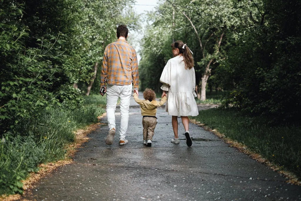 mom and dad walking with toddler in the park