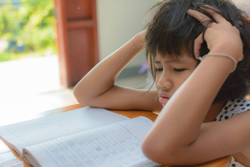 Stressed schoolgirl at her desk trying to finish homework