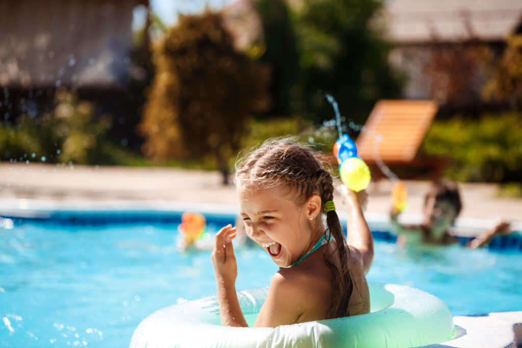 Children having fun playing with water guns in the swimming pool