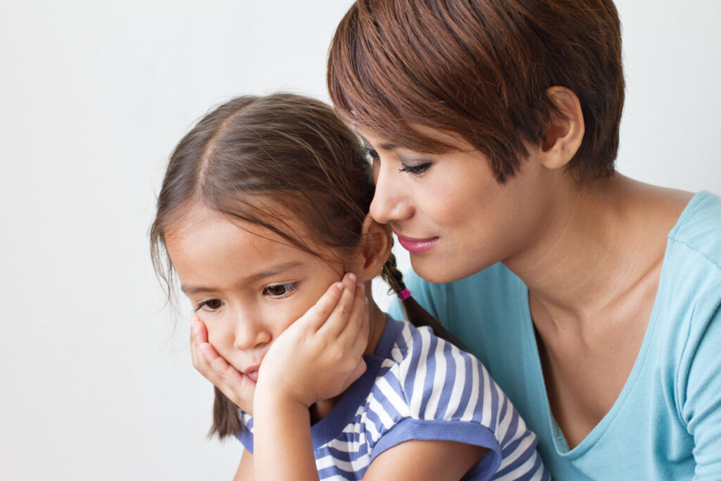 Calm mother holding her preoccupied daughter