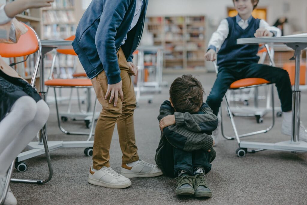 Little boy with face covered, surrounded by other kids bullying him.