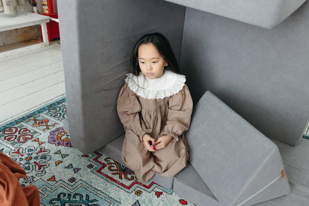 Sad little girl kneeling in a time out corner.