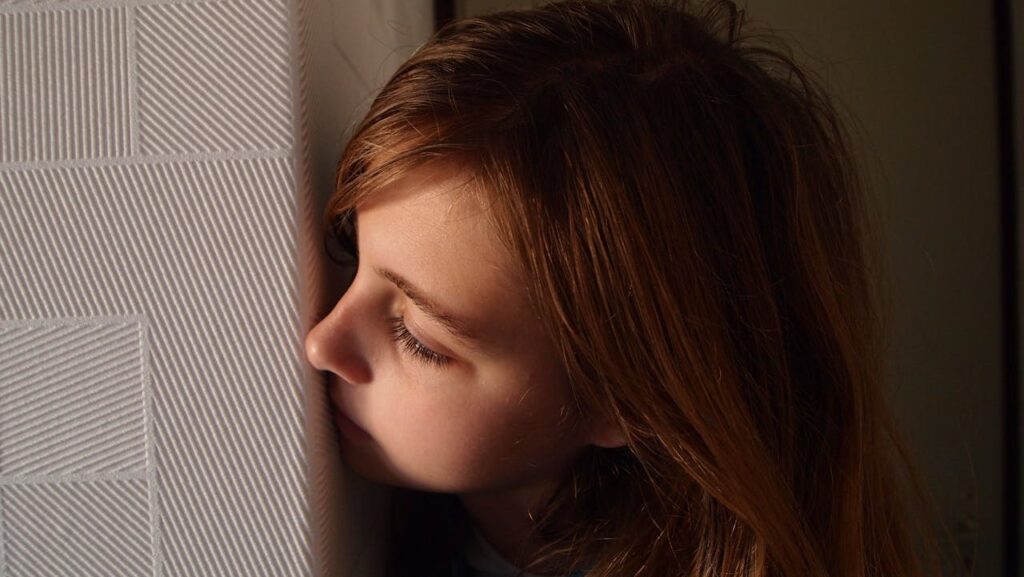 Profile portrait of a girl looking fearfully around a corner while in time out.