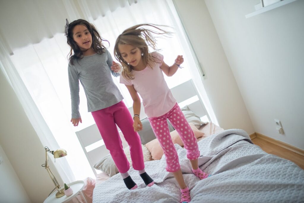 two girls jumping in bed