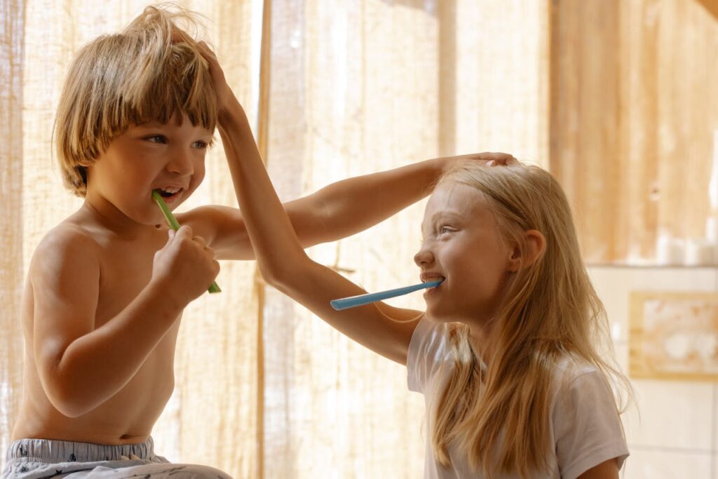 siblings having fun while brushing teeth together