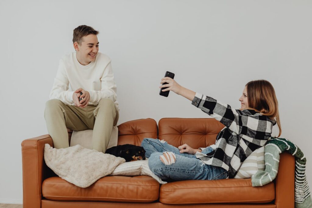 teenager couple on the sofa, looking at the screen of smartphone